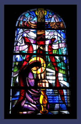 stained glass depicting Mary Magdalene at the foot of the cross